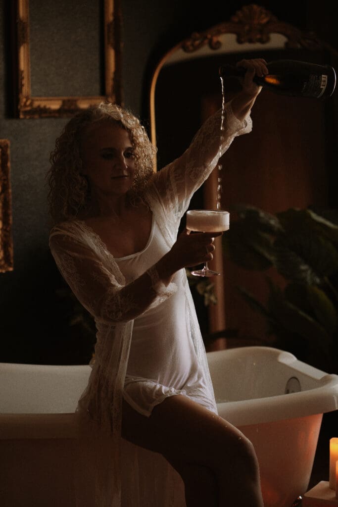 What Actually Changes After Your Second Boudoir Session: Woman confidently pouring champaign during her second boudoir experience with Onyx and Sage Studios at The Onyx Haus.