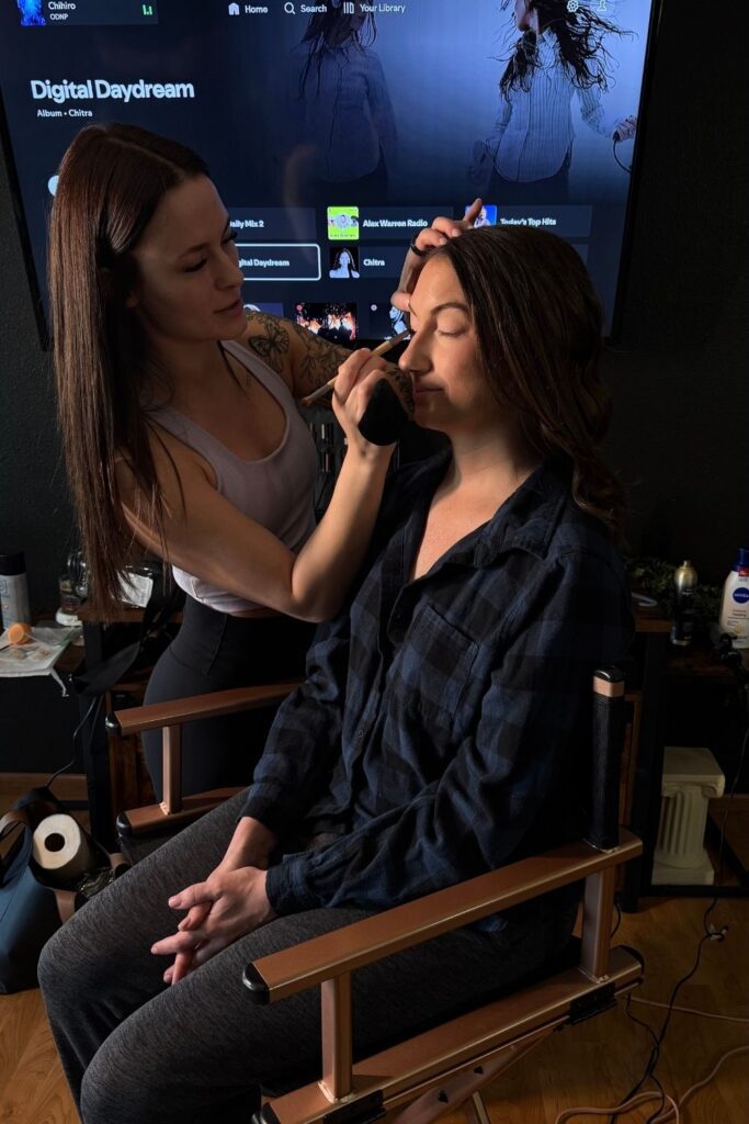Woman getting hair and makeup done, feeling a mix of confidence and nerves before session