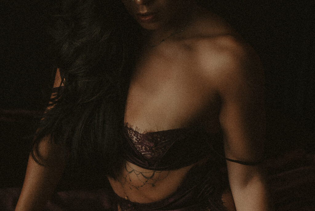Tattooed woman in lace lingerie during an intimate boudoir photography session at Onyx & Sage Studios in Minnesota.
